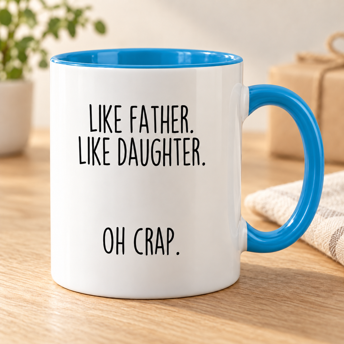Like Father, Like Daughter, Oh Crap coffee mug — Blue variant, photographed on an oak table.