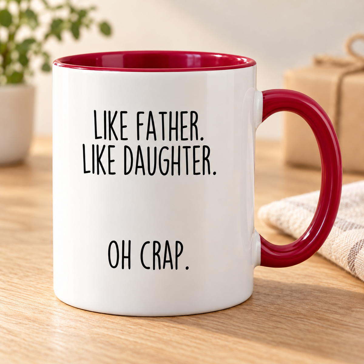 Like Father, Like Daughter, Oh Crap coffee mug — Red variant, photographed on an oak table.