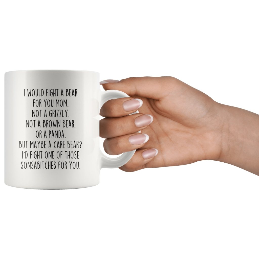 Hand holding the white "I Would Fight a Bear for You Mom" mug by its handle